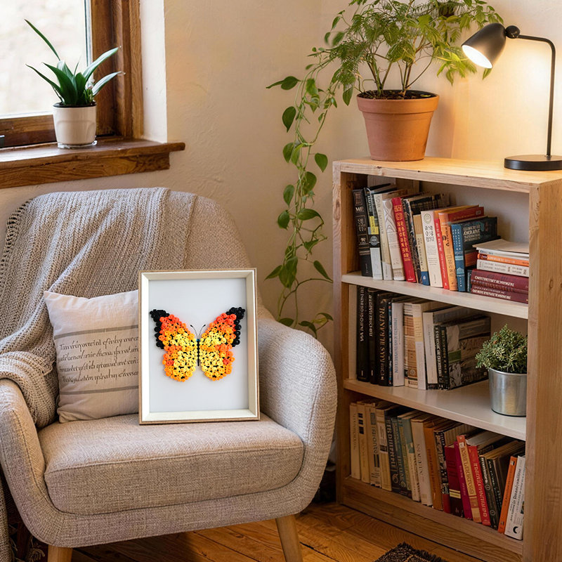 Framed butterfly button artwork on a chair next to a bookshelf with books and plants.